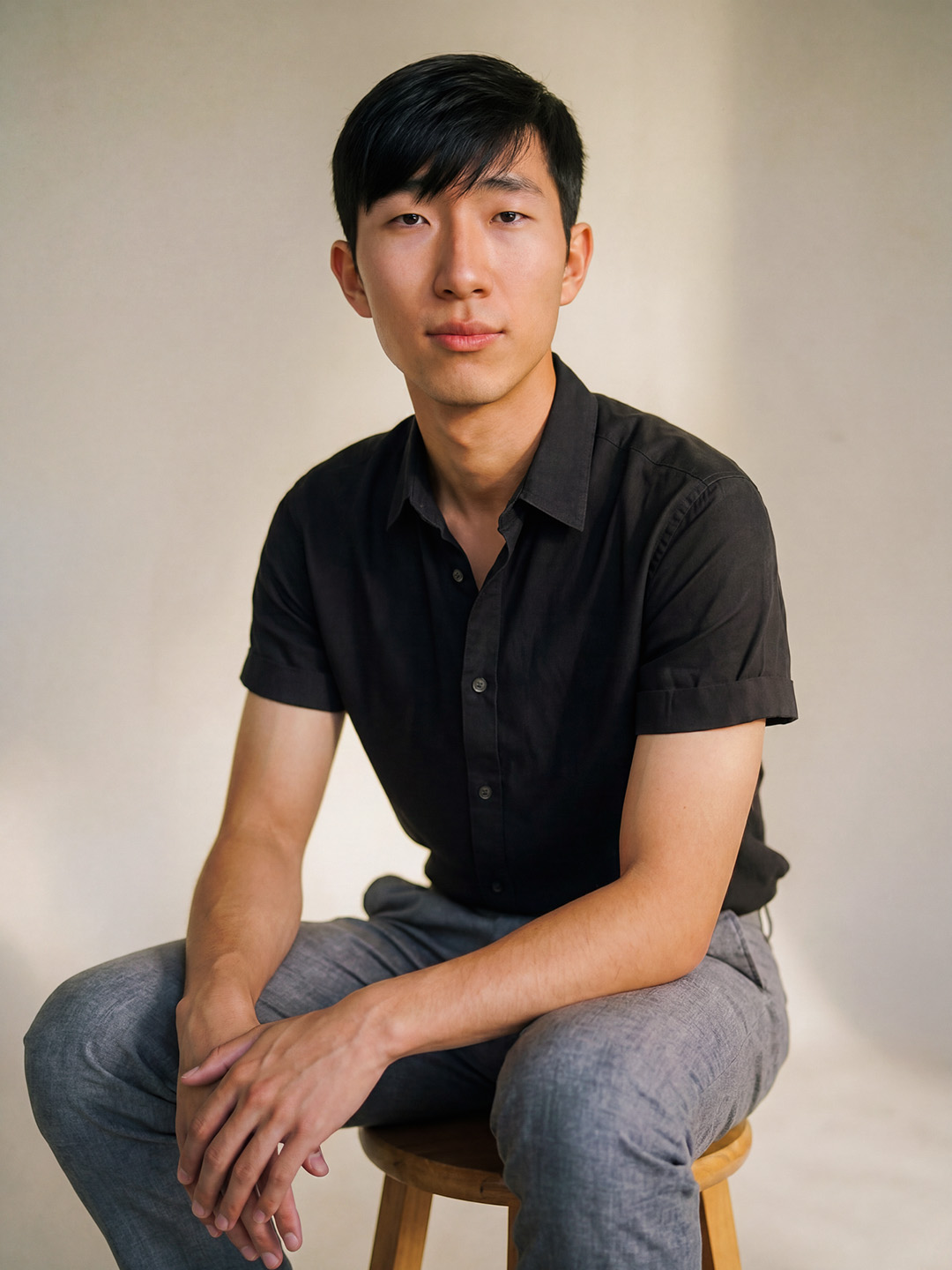 a smiling, handsome dark-haired person poses for a portrait in a black t-shirt