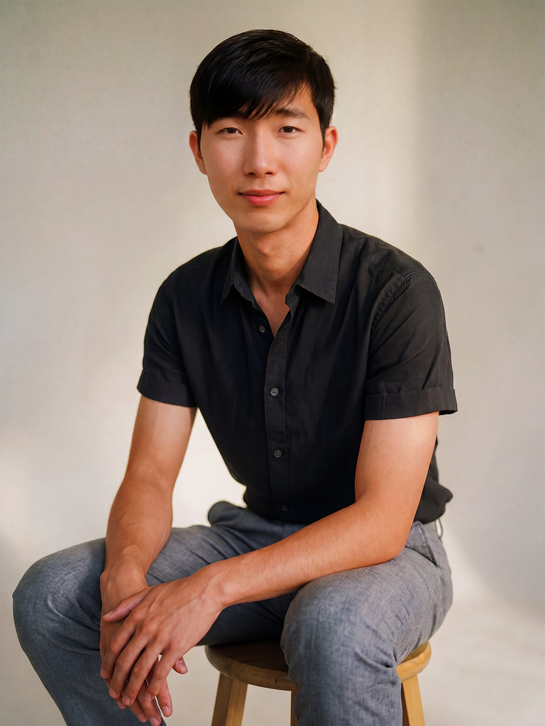 a smiling, handsome dark-haired person poses for a portrait in a black t-shirt
